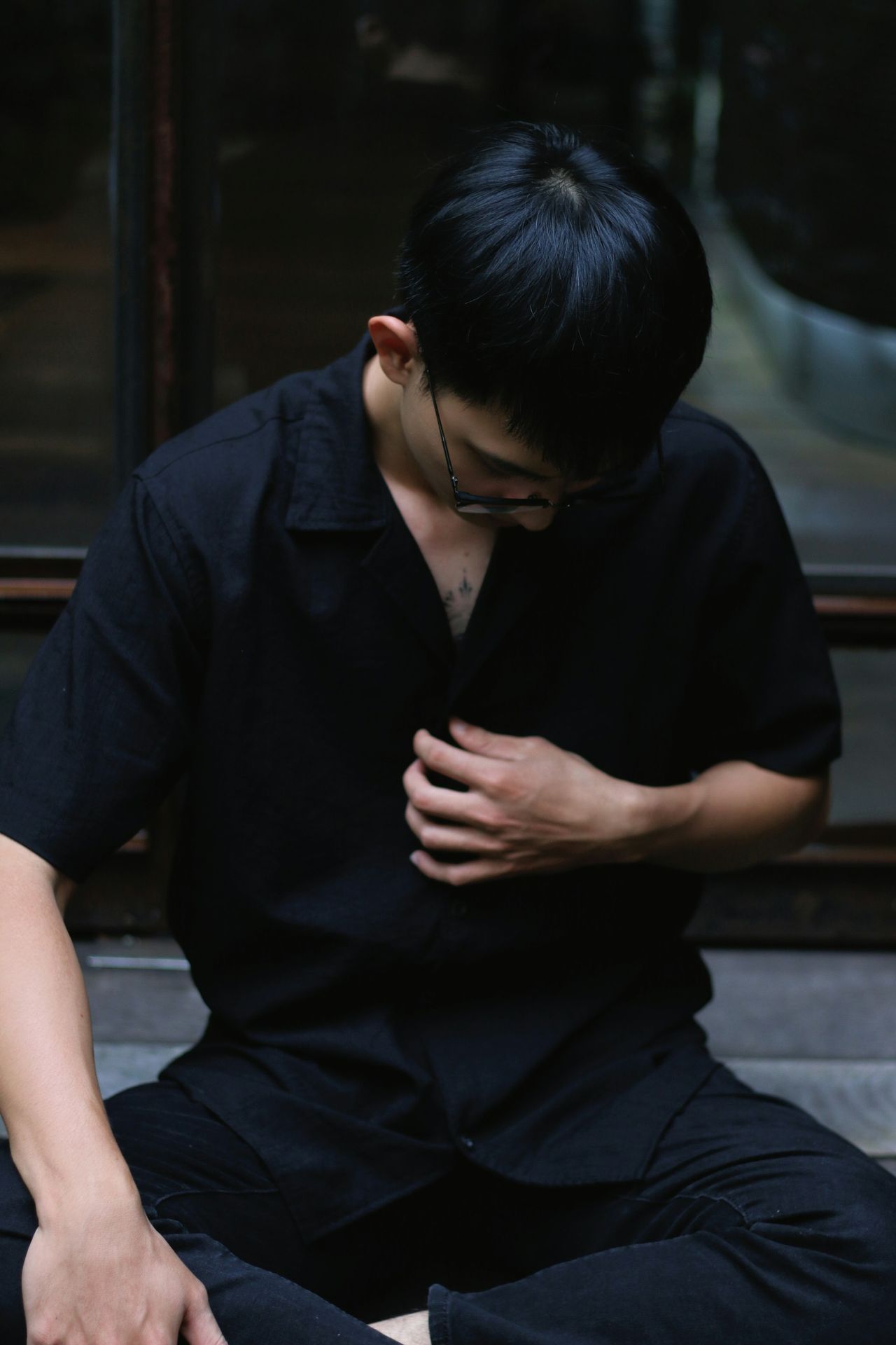 a man sitting on the ground holding his hands together